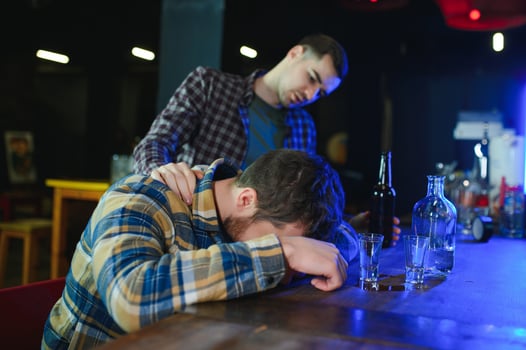 Sad young man sitting at bar counter in pub. Upset man drinks alcohol because of problems at work. photo