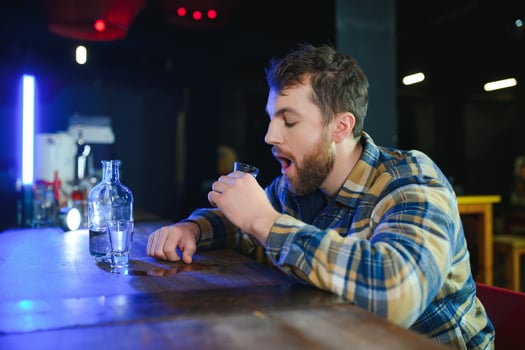 It was a hard day. Depressed young man drinking vodka in bar photo