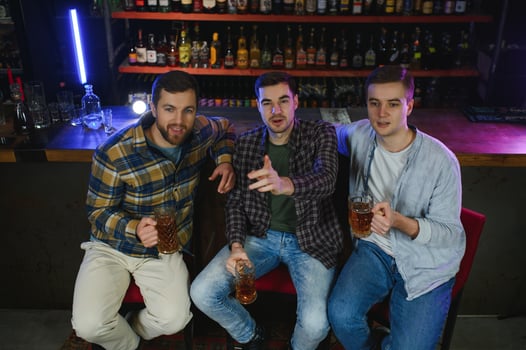 Soccer fans at the bar. Happy football fans cheering at bar and drinking beer while bartender serving beer at the background photo