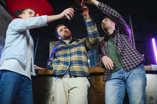 Old friends meeting. Happy young men in casual wear toasting with beer while sitting in beer pub together photo