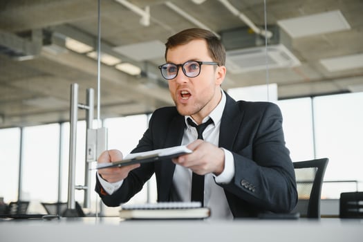 Angry businessman sitting at his desk and screaming at his employees. photo