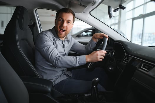 Visiting car dealership. Handsome bearded man is stroking his new car and smiling. photo
