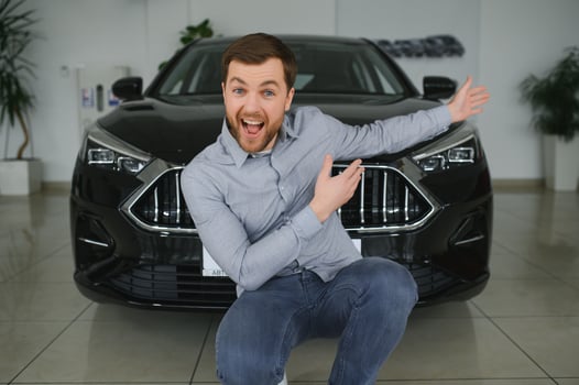 Visiting car dealership. Handsome bearded man is stroking his new car and smiling photo