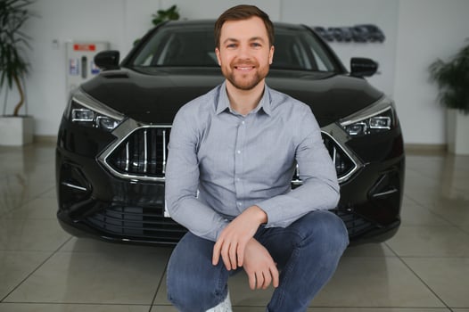 Visiting car dealership. Handsome bearded man is stroking his new car and smiling photo