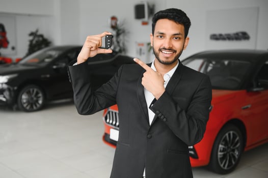 Good looking, cheerful and friendly indian salesman poses in a car salon or showroom. photo