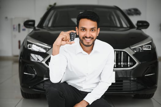 Good looking, cheerful and friendly indian salesman poses in a car salon or showroom. photo