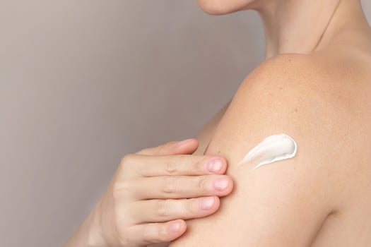 Naked caucasian woman spreads cream on her shoulders, takes care of herself, swatch of a cream. copy space nude background cropped photo