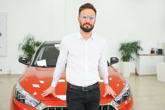 Happy young guy checking new luxury car, buying automobile at dealership centre. Portrait of cheerful millennial Caucasian man examining auto at showroom store photo