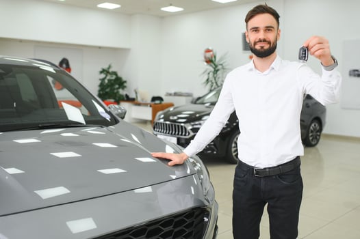 Yes, that's my new car. Customer in car dealership. Young man with keys in hand photo