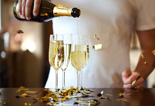 Champagne Flutes In Golden Sparkle Background with golden confetti. Man pouring sparkle wine photo