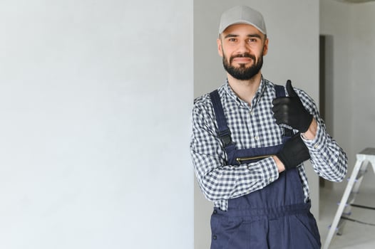 smiling repairman standing near stepladder and looking at camera photo