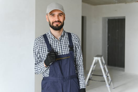 smiling repairman standing near stepladder and looking at camera photo