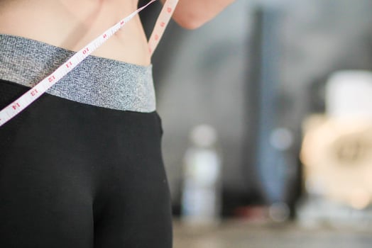 A young woman holds a tape measure to measure her waist circumference after exercising to reduce belly fat and measures her waist circumference to check the results of the weight loss course. photo