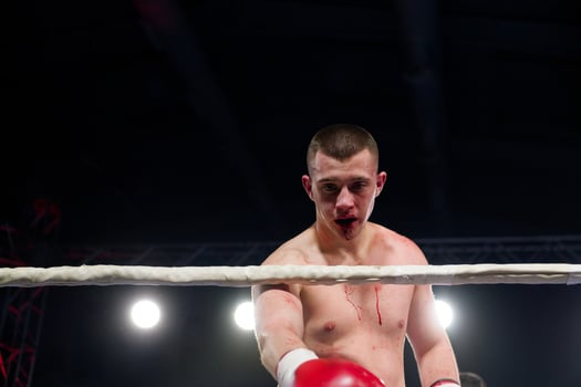 A bloodied boxer basks in the glory of victory, saluting the crowd after a grueling fight. photo