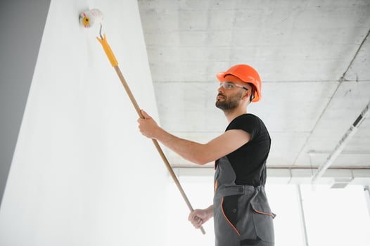 Building contractor painting grey wall with roller brush photo