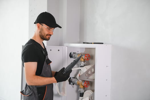 The worker installs or inspects Fire extinguisher and fire hose reel in building corridor photo