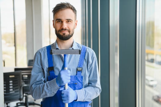 Young man cleaning window in office photo