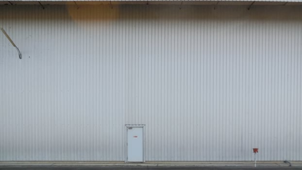 outer wall of a large warehouse with access doors for caregivers. The metal wall background of the spacious storage warehouse and caretaker entrance on the wall also provides space for messages. photo
