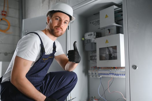 A male electrician works in a switchboard with an electrical connecting cable. photo