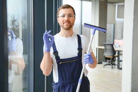 Young man washing window in office photo
