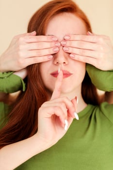 Deaf woman with covered eyes gesturing silence photo