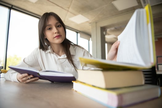 Teen girl studying with textbook writing essay learning in classroom. photo