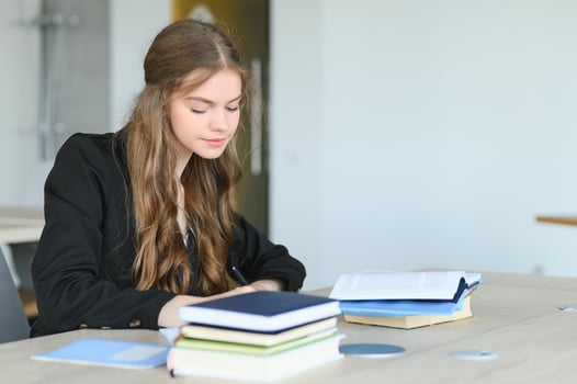 Teen girl studying with textbook writing essay learning in classroom. photo