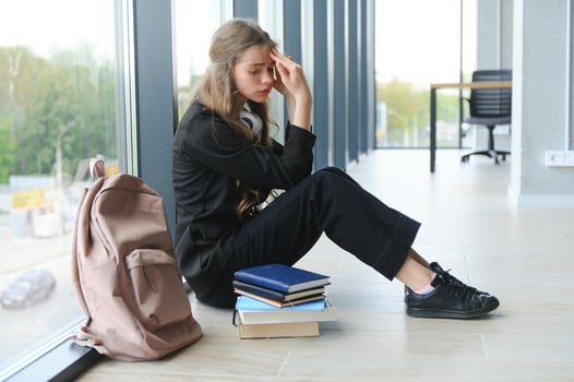 Lonely sad schoolgirl while all her classmates ignored her. Social exclusion problem. Bullying at school concept. photo