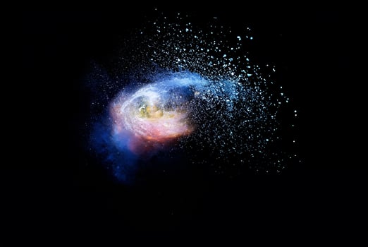 Abstract brown powder explosion. Closeup of blue dust particle splash isolated on black background. photo