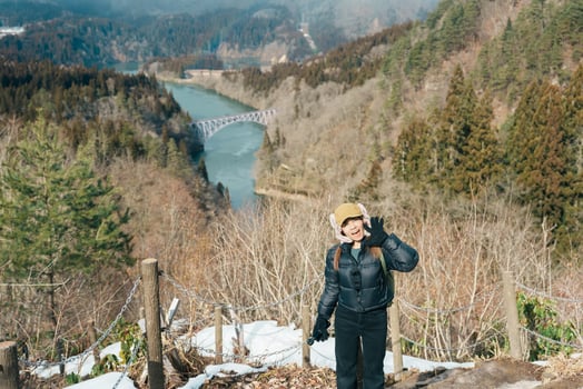 Woman tourist sightseeing View of Japan local train with Tadami river and bridge. Traveler travel at Tadami Railway Line in Mishima Machi, Aizu, Fukushima Prefecture, Japan. Landmark and iconic spot photo