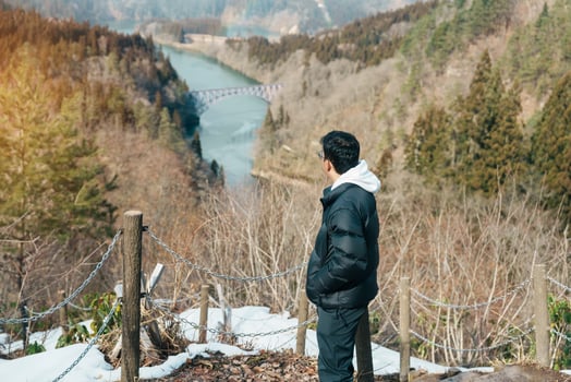 man tourist sightseeing View of Japan local train with Tadami river and bridge. Traveler travel at Tadami Railway Line in Mishima Machi, Aizu, Fukushima Prefecture, Japan. Landmark and iconic spot photo