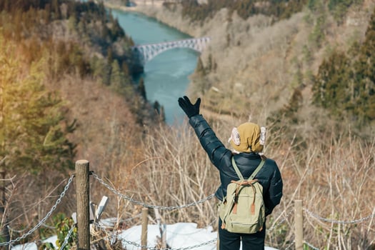 Woman tourist sightseeing View of Japan local train with Tadami river and bridge. Traveler travel at Tadami Railway Line in Mishima Machi, Aizu, Fukushima Prefecture, Japan. Landmark and iconic spot photo