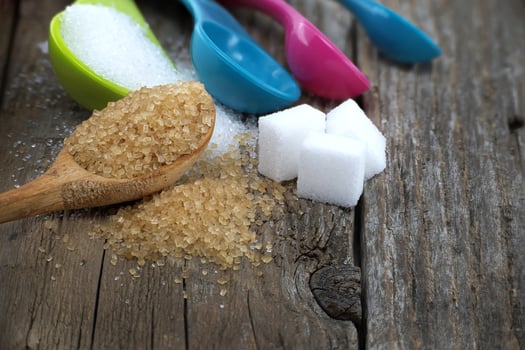 Brown cane sugar and white sugar in measuring spoons photo