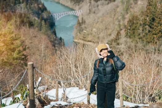 Woman tourist sightseeing View of Japan local train with Tadami river and bridge. Traveler travel at Tadami Railway Line in Mishima Machi, Aizu, Fukushima Prefecture, Japan. Landmark and iconic spot photo