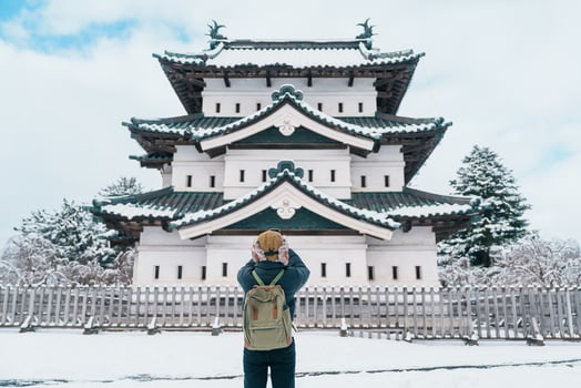 Woman tourist sightseeing Hirosaki Castle in winter, happy traveler travel Hirosaki city, Aomori Prefecture, Tohoku, Japan. Landmark and famous for tourist attraction. Japan travel and vacation photo