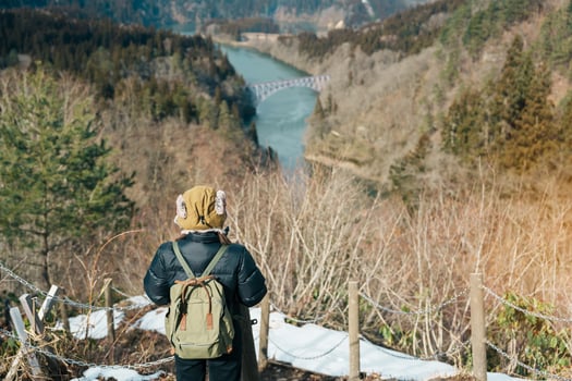 Woman tourist sightseeing View of Japan local train with Tadami river and bridge. Traveler travel at Tadami Railway Line in Mishima Machi, Aizu, Fukushima Prefecture, Japan. Landmark and iconic spot photo