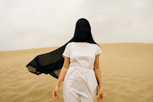 girl in white dress with a black scarf on the head in desert. photo
