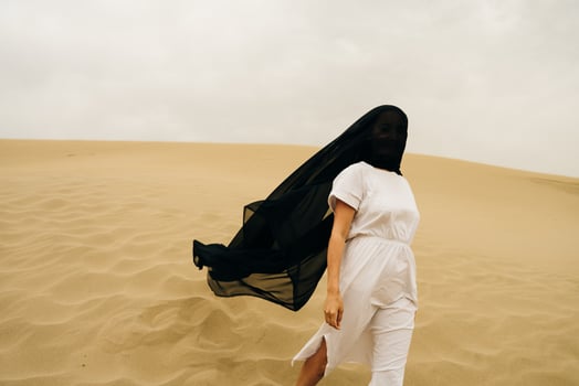 girl in white dress with a black scarf on the head in desert. photo