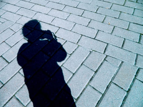 silhouette shadow of a girl with a camera on the background of road masonry photo