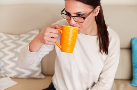 Happy female freelancer with coffee cup on couch at home photo