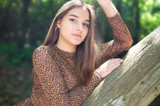 Emotional girl teenager with long hair hairstyle braids in a green shirt sits on a bench in the park. photo
