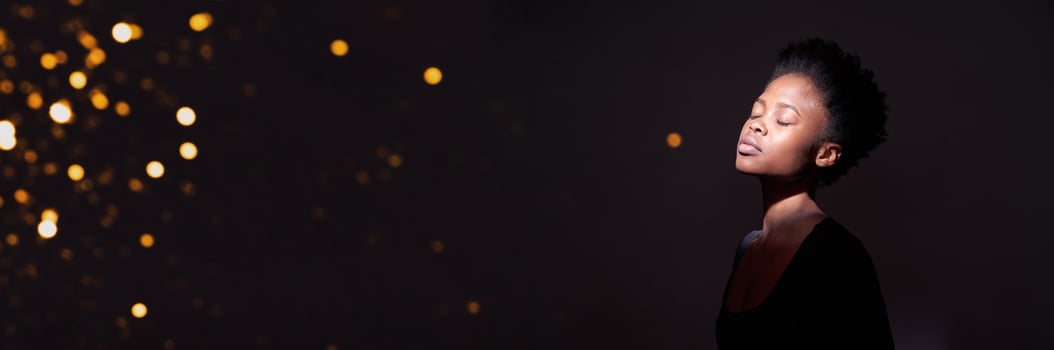 A black banner with sequins and a portrait of an African-American woman with short hair and closed eyes. With space to copy photo
