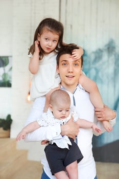Portrait of a happy young father with a baby son and little daughter at home photo