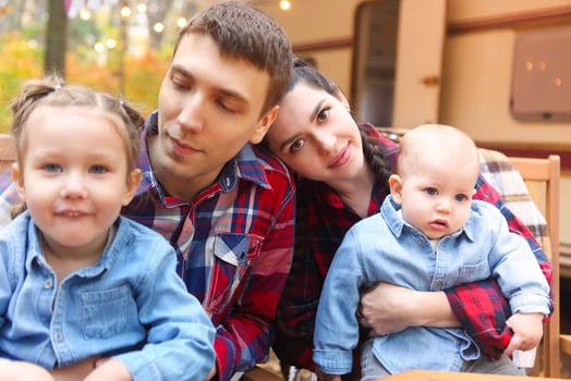 Portrait of a young smiling family while hugging near house on wheels photo