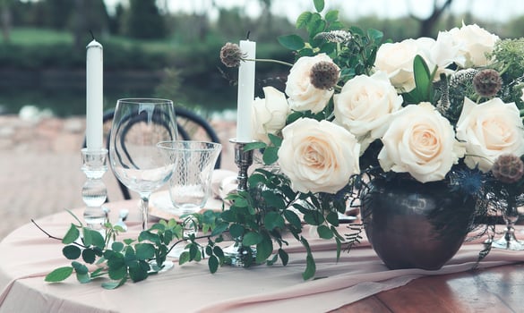 Candles and vase with white roses placed on round table near wineglasses photo