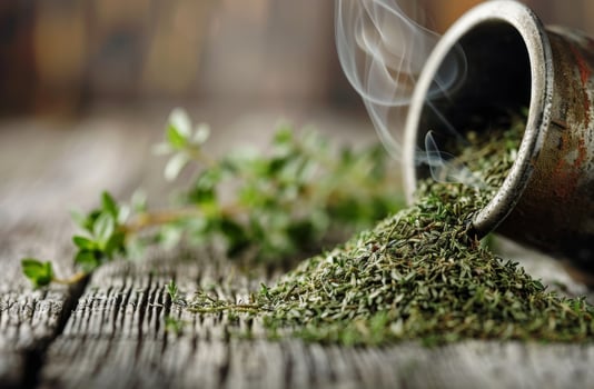 Dried Thyme Spilling From Mortar on Wooden Table photo