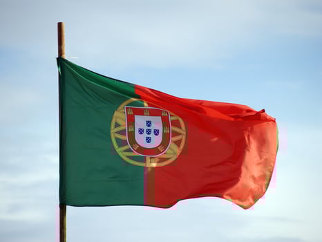 Portuguese flag waving proudly in the wind, showcasing its vibrant colors and emblematic design against a clear blue sky. photo