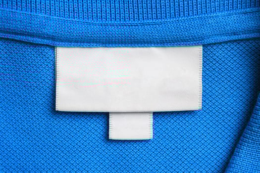 Blank white laundry care clothes label on blue shirt fabric texture background photo