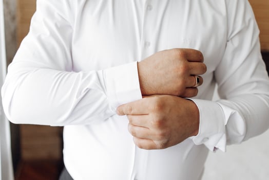A man in a white shirt is getting ready to put on his wedding ring. He is adjusting his shirt and sleeves, and his hands are visible. Concept of preparation and anticipation for a special occasion photo