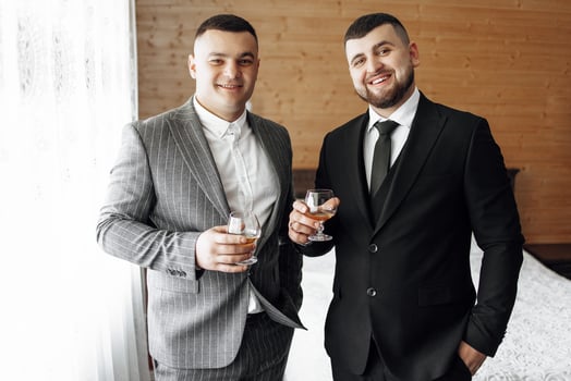 Two men in suits are standing next to each other, holding glasses of wine photo